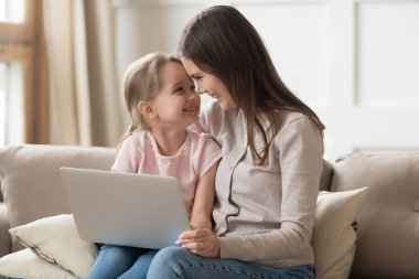 Sevgi dolu genç anne ve kız alınlarına dokunuyor, dizüstü bilgisayar kullanıyor.