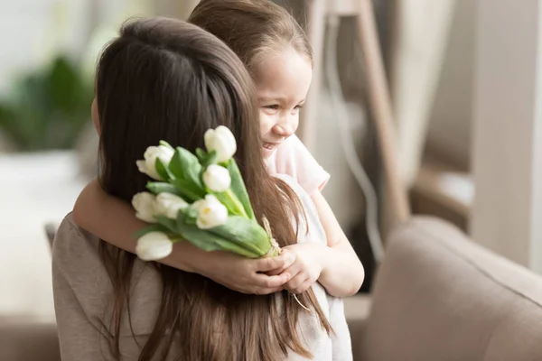 Petite fille embrassant, félicitant la mère, présentant des fleurs — Photo
