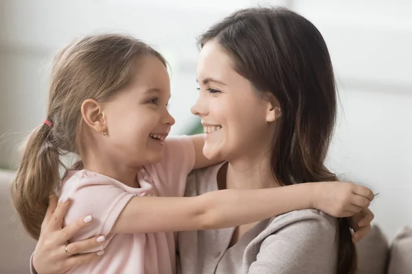 Усміхнена мати і маленька дочка обіймаються, дивлячись в очі — стокове фото