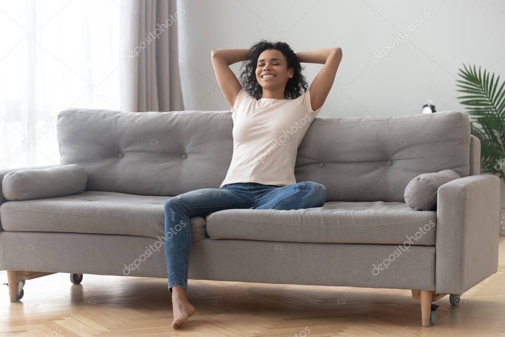 Serene smiling african woman resting on couch at home