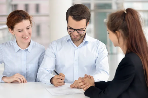 Emocionado contrato de firma de pareja cerrando contrato en la oficina de bienes raíces — Foto de Stock