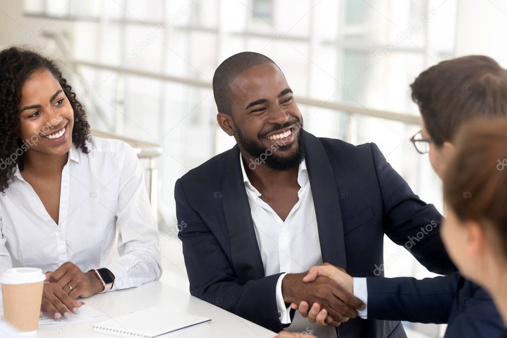 Smiling black businessman handshake male partner at meeting