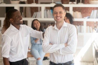 Çok ırklı, heyecanlı iş adamları ofiste birlikte poz veriyorlar.