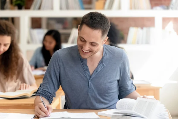 Smiling male student studying in library preparing for test — ストック写真