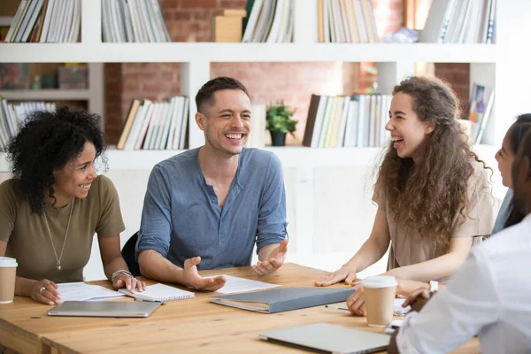 Smiling multiracial millennial colleagues laugh talking at meeting — ストック写真