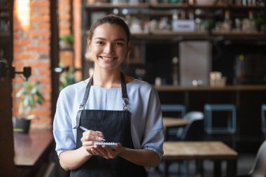 Önlüklü gülümseyen garsonun portresi kameraya bakıyor.