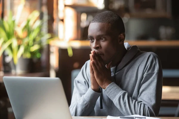 Надежный черный парень надеется на лучшее чтение новостей на ноутбуке — стоковое фото