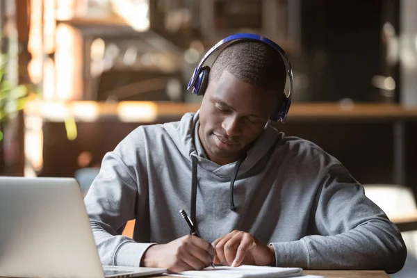 Концентрированный черный студент в наушниках Bluetooth, изучающий — стоковое фото