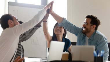Aşırı neşeli çeşitli çalışanlar ofis toplantısında beşlik çakıyor.