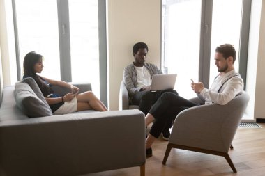 Çeşitli bin yıllık çalışanlar ofisteki cihazları kullanmakla meşgul.