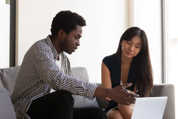 Millennial multiracial colleagues talk brainstorming on laptop