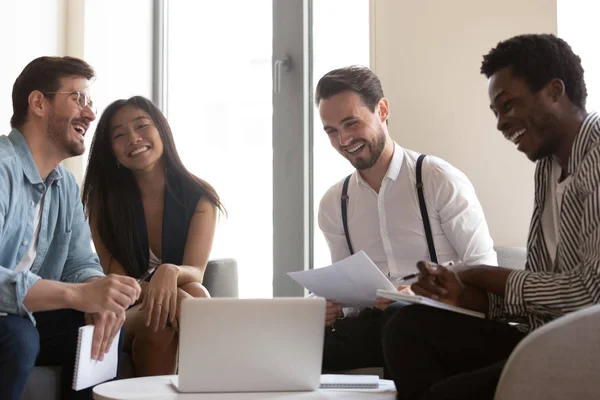 Diversos colegas sonrientes se ríen cooperando en la reunión informativa en la oficina — Foto de Stock