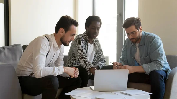 Empresarios multirraciales discutiendo proyecto de negocio en portátil en la oficina — Foto de Stock