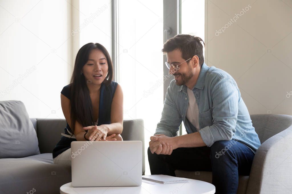 Diverse coworkers brainstorming using laptop in office