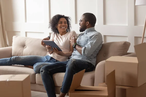 Sorrindo casal familiar preto sentado no sofá com tablet . — Fotografia de Stock