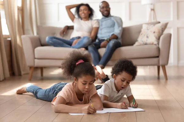 Mixed race brother and sister coloring pictures, lying on floor. — Stock Photo, Image