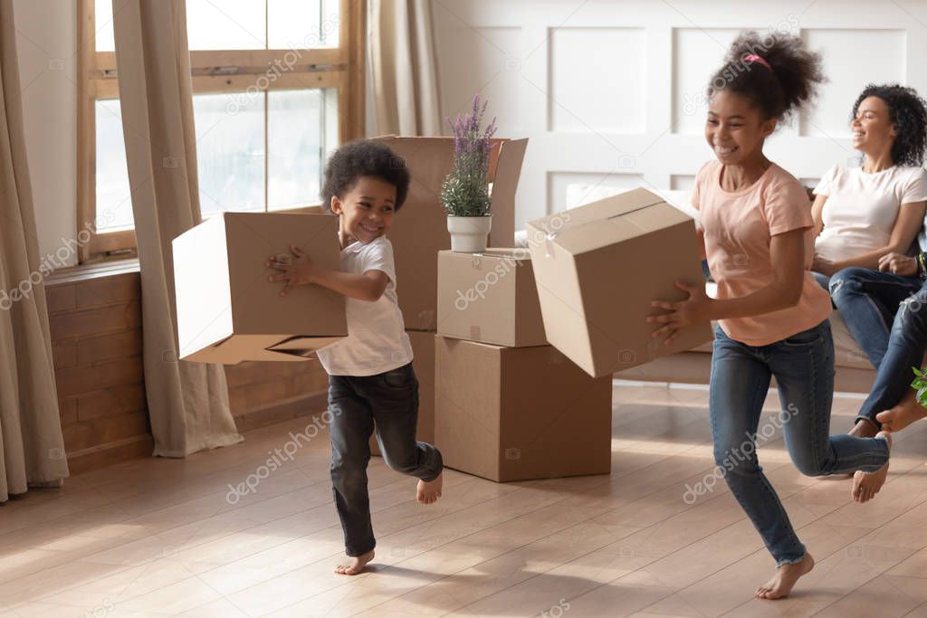 Overjoyed black kids running, playing with carton boxes.