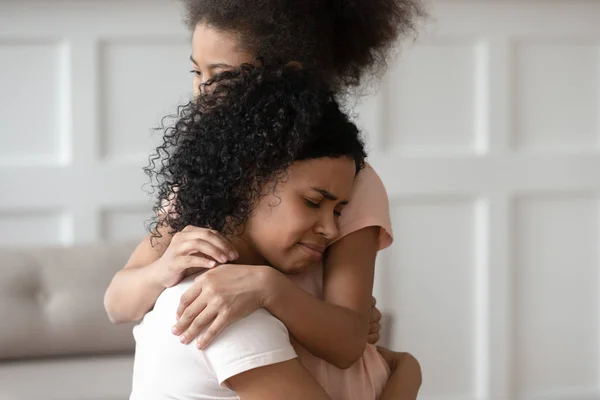 Close up sad upset black woman cuddling daughter. — Stock Photo, Image