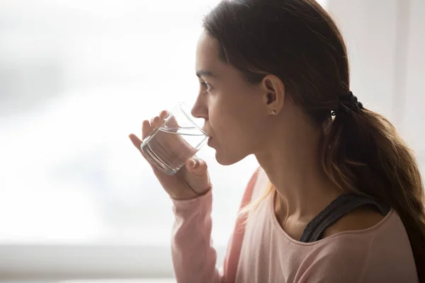 Тысячелетняя многонациональная девушка пьет стакан чистой воды . — стоковое фото