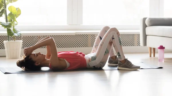 Mujer joven en forma deportiva relajándose en la esterilla de yoga en casa . — Foto de Stock