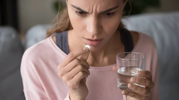 Stressed young woman holding pill and glass of water. — Stock Photo, Image