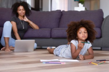 Küçük kız ev zemininde resim yapmayı düşünüyor.