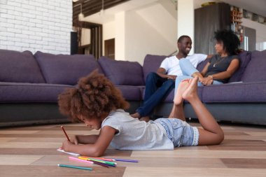 Küçük bir kız yere uzanmış, anne babası dinleniyor.