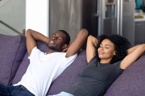 Calm black couple relax on cozy couch taking nap