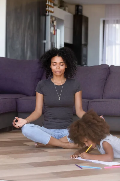 Afro-americano mãe meditando com filha pintura de lado — Fotografia de Stock