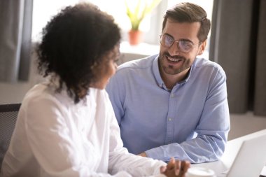 Gülümseyen adam iş arkadaşı ile laptopta sohbet ediyor.