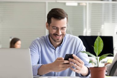 Gülümseyen adam işe ara verdi. Akıllı telefondan mesaj atıyor.