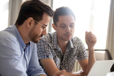 Odaklanmış erkek meslektaşlarım laptopta çalışırken beyin fırtınası yaptılar.