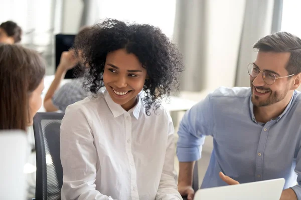 I colleghi sorridenti parlano lavorando insieme sul computer portatile in ufficio — Foto Stock