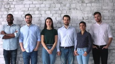 Çok ırklı profesyonel iş adamları sıraya girip kameraya bakıyor.