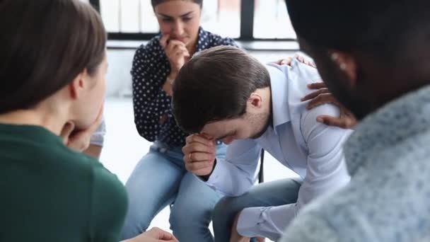 Грустный плачущий мужчина делится проблемой во время групповой терапии — стоковое видео