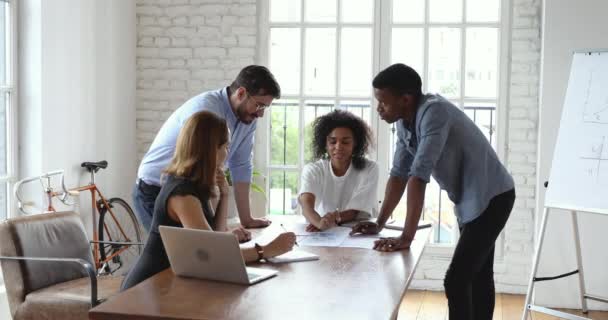 Jovens colegas de equipe multiétnicos criativos analisando relatórios em papel — Vídeo de Stock