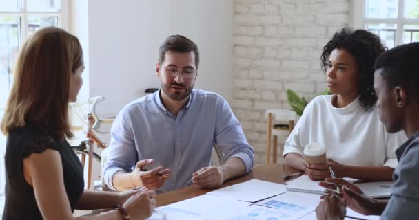 Multiraciální spolupracovníci poslouchají vedoucího týmu v brýlích. — Stock video