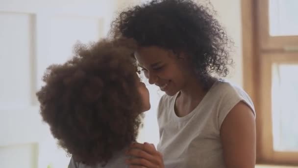 Heureuse femme afro-américaine touchant le nez avec une petite fille mignonne . — Video