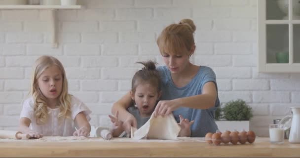 Lächelnde Mutter bringt kleinen Töchtern das Backen von Gebäck bei. — Stockvideo