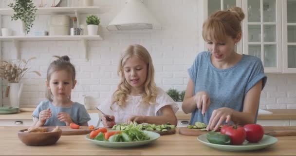 Cheerful young babysitter nanny talking to small sisters, teaching cooking. — Stock Video