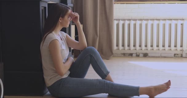 Przygnębiona młoda kobieta siedząca na podłodze, zdesperowana. — Wideo stockowe