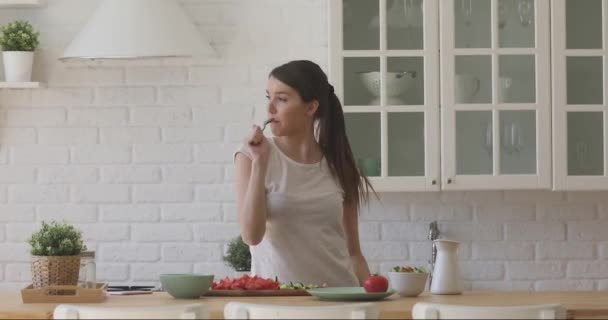 Podekscytowana kobieta śpiewa ulubioną piosenkę podczas zdrowego gotowania żywności. — Wideo stockowe