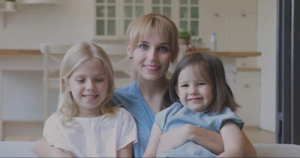 Счастливая привлекательная молодая женщина обнимает маленьких милых дочерей . — стоковое видео