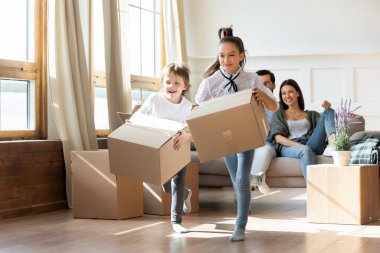 Heyecanlı çocuklar taşınma gününde kutuları açarken eğleniyorlar.