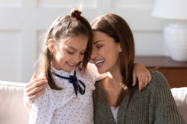 Sevgi dolu genç anne ve küçük kız evde sarılıyorlar.