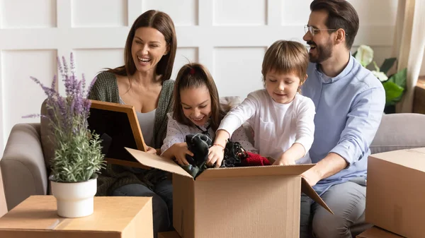 Familia emocionada con niños pequeños se instalan en casa nueva — Foto de Stock