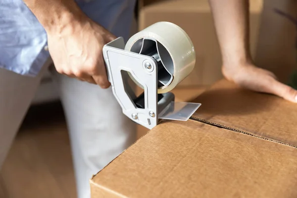 Male renter seal boxes with adhesive scotch moving — Stock Photo, Image