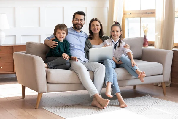 Happy young family sit on couch using modern laptop — Stock Photo, Image