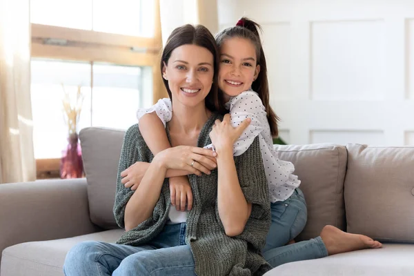 Cute little girl hug happy mom relax on couch together — Stock Photo, Image