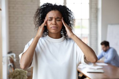 Baş ağrısı çeken, şakaklara dokunan Afrikalı Amerikalı iş kadını.